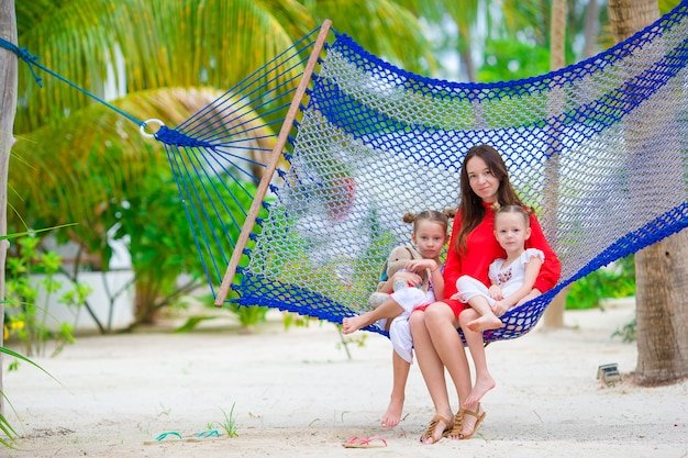 mother-two-kids-sitting-hammock-tropical-beach_109800-7401